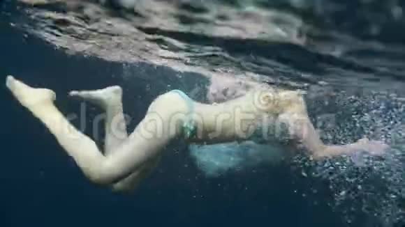 在许多气泡中漂浮在水中的瘦小女子视频的预览图