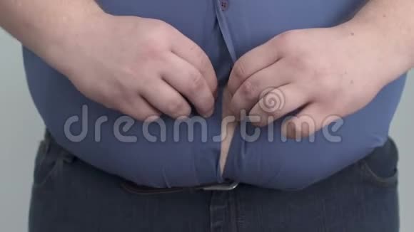 肥胖男人把衬衫扣在巨大的肚子上与不安全肥胖作斗争视频的预览图