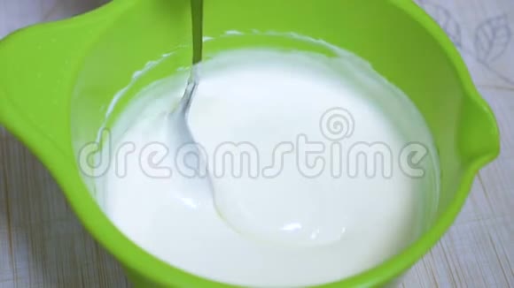 家庭主妇用勺子混合酸奶油蛋糕视频的预览图