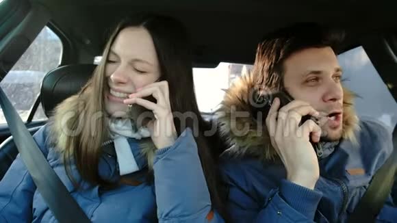 男人和女人说他们的手机和歇斯底里的笑坐在车里视频的预览图