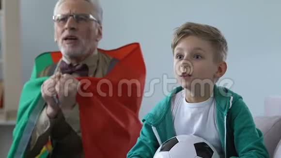 在庆祝葡萄牙队胜利的电视比赛中有孙子的老人大声喊叫视频的预览图