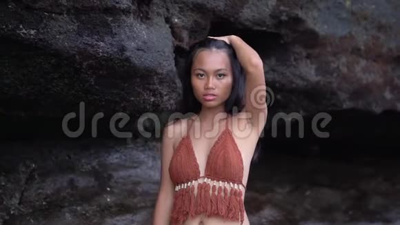 Fablim东方模特穿着黑色岩石下的棕色泳衣为相机摆姿势视频的预览图
