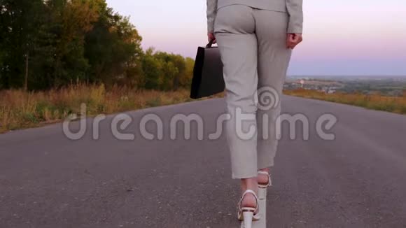 女商人左手拿着黑色公文包手里拿着文件女商人穿着长裤和白色的柏油路走着视频的预览图