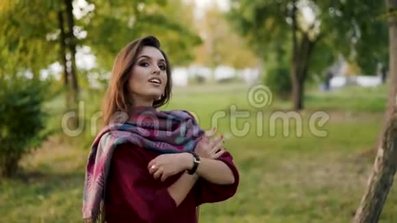 公园里戴着时尚围巾的自信女孩在镜头前交叉双手的肖像视频的预览图
