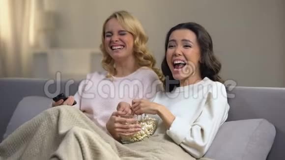 两个年轻的女孩看着带爆米花和笑声的喜剧闲暇时间在家视频的预览图