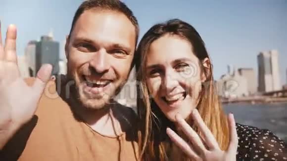喜笑颜开的年轻新婚夫妇在网上与朋友视频聊天在纽约的曼哈顿天际线风景视频的预览图