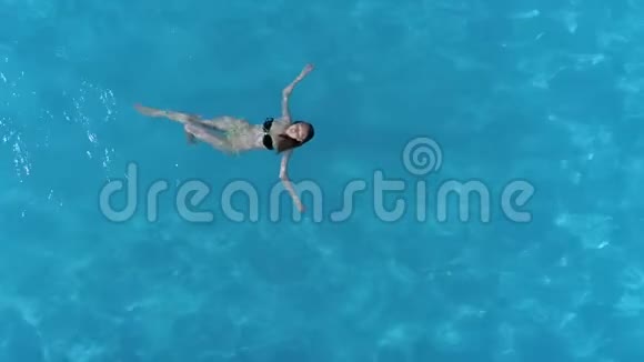 泳池里漂浮着的女孩享受着清澈的水享受着暑假空中景色视频的预览图