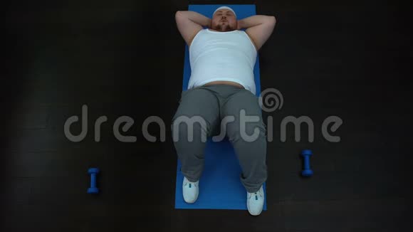 疲惫的肥胖男性在家做腹部按摩努力的健身计划懒惰视频的预览图