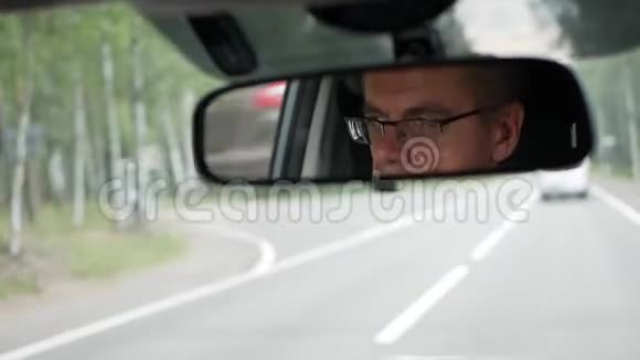 老人在乡间路开车汽车后视镜中的面部反射特写视频的预览图