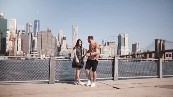微笑的白种人夫妇离开史诗般的纽约景观附近的曼哈顿天际线牵手快乐的慢动作视频的预览图