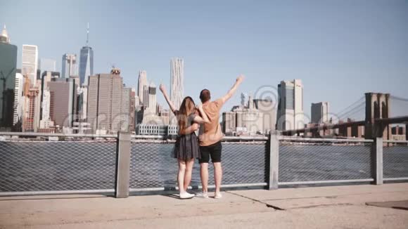 幸福的白种人情侣拥抱在一起双臂高举在纽约曼哈顿迷人的天际线上慢条斯理地走着视频的预览图