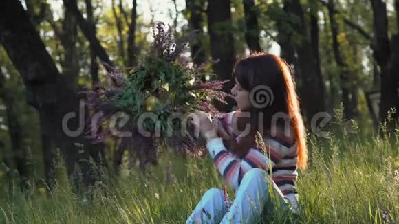 美丽的女孩在森林的一片草地上在早晨坐着一朵迎春花视频的预览图