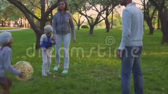 父母和两个女儿在盛开的果园里的春天公园里玩球积极的休闲视频的预览图