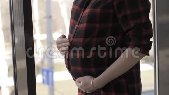 美丽的孕妇站在艺术工作室的窗户附近视频的预览图