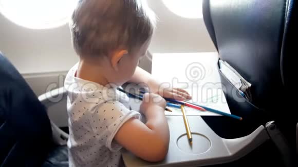 小男孩在飞机折叠桌上用彩色铅笔画画的4k镜头视频的预览图