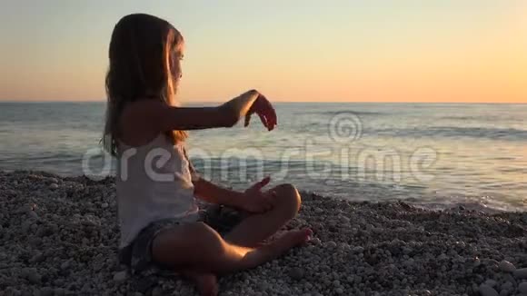 在日落时沙滩上玩耍的孩子小女孩在海水中扔泡视频的预览图