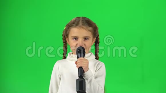 小女孩在演播室的绿色屏幕上对着麦克风唱歌视频的预览图