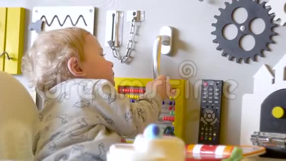 为孩子们准备的繁忙的棋盘可爱的小男孩在墙上玩忙碌的木板视频的预览图