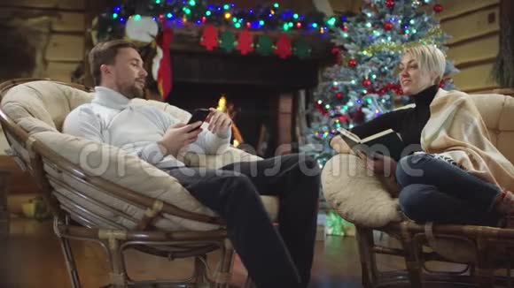 男人和女人在圣诞夜边看书边用智能手机聊天视频的预览图