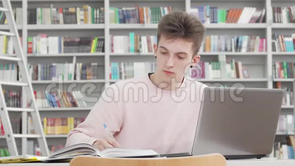 在大学图书馆工作的年轻男学生视频的预览图
