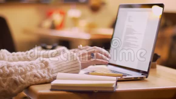 在一家舒适的咖啡店里女性手在笔记本电脑上打字的特写镜头视频的预览图