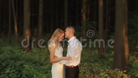 一对温柔的新婚夫妇面对面地站在森林里新郎正在拥抱新娘慢动作视频的预览图