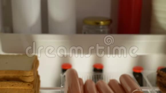 贪得无厌的肥胖男人晚上在冰箱附近吃香肠塑料盖消费主义视频的预览图