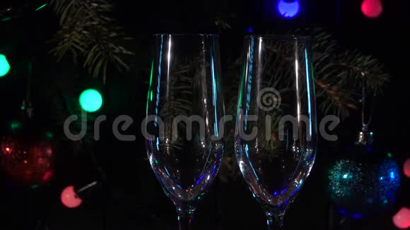两杯泡沫香槟在闪烁的灯光背景下有气泡慢动作关门视频的预览图