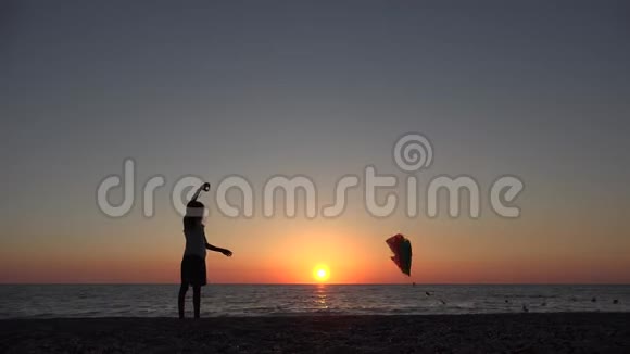 沙滩上玩飞风筝的孩子日落时的孩子海岸上的快乐女孩视频的预览图