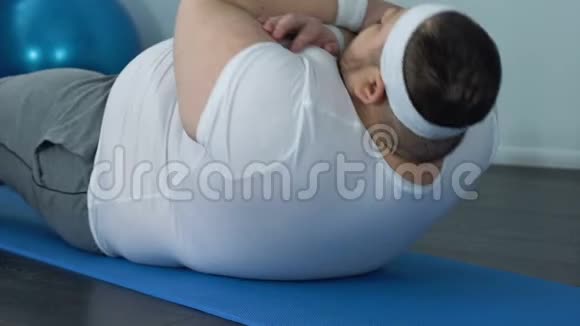 肥胖男性肥胖的腹部做仰卧起坐运动垫子上做仰卧起坐运动健身课视频的预览图