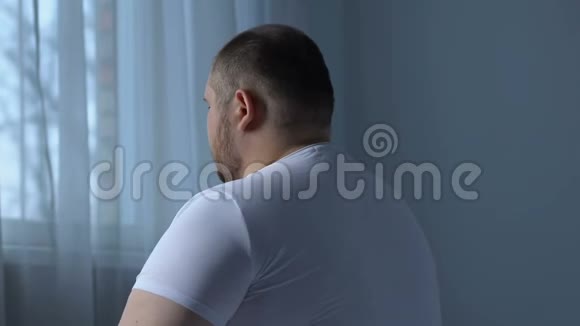 肥胖男性坐在床上做背部运动缺乏运动伸展肌肉视频的预览图