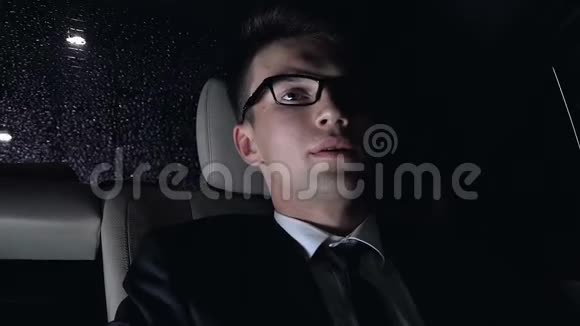 劳累过度的商人头痛坐在车后座上晚上视频的预览图