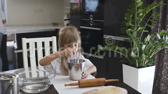 当妈妈在厨房忙着做面团时特写小女孩用勺子搅拌面粉小美女视频的预览图