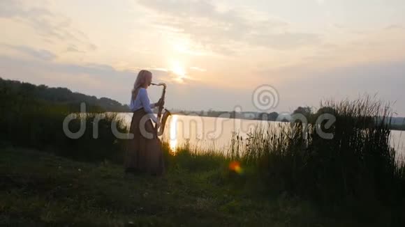 年轻漂亮的浪漫女孩坐在地上的干草上手里拿着萨克斯管一个拿着乐器的女人视频的预览图