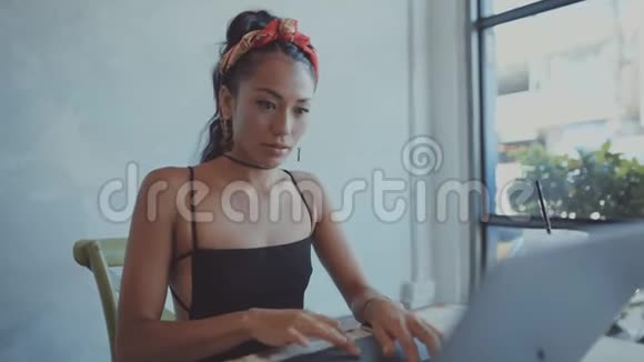 美丽的年轻亚洲女孩在一家带笔记本电脑的咖啡店工作在咖啡店工作的女性自由职业者视频的预览图