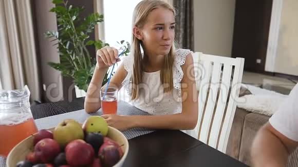 美丽的家庭在家里的厨房里一起吃早餐十几岁的女孩喝果汁她父亲也喝视频的预览图