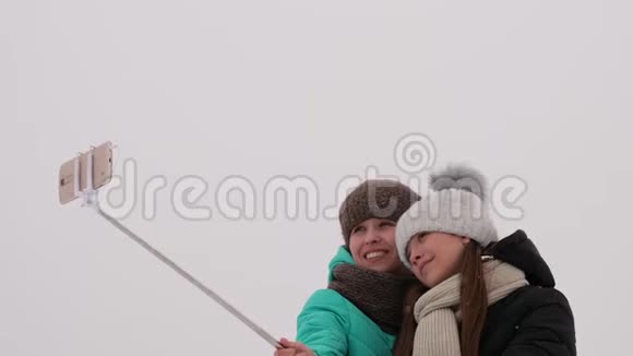 妈妈和女儿在智能手机上拍照在圣诞节早上的冬天公园视频的预览图