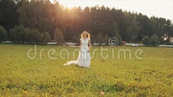 一位美丽的新娘朝田野里的照相机跑去背景中惊人的景观慢动作视频的预览图