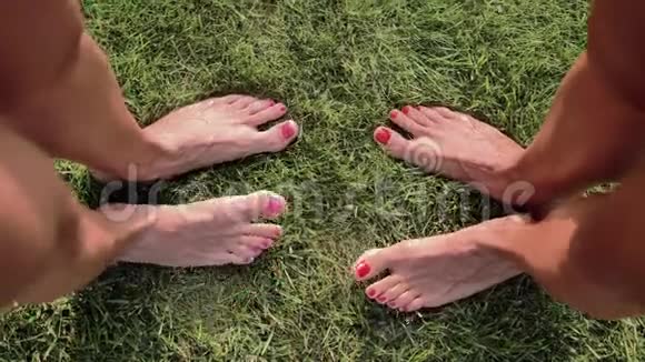 两对雌性的双脚站在绿草地上视频的预览图