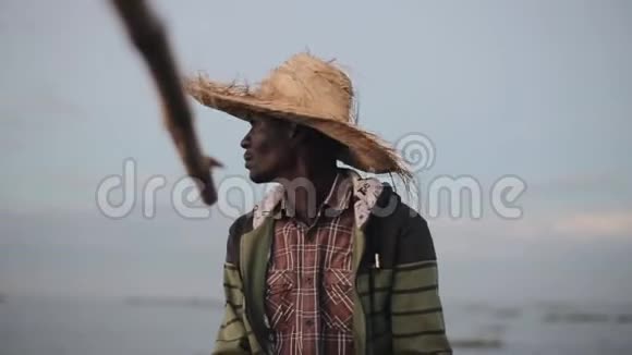 戴草帽的非洲渔夫肖像年轻人坐在船上独自钓鱼视频的预览图