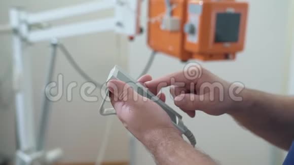 关闭男医生手在医院用遥控器设置机器x光诊所的医疗工具视频的预览图