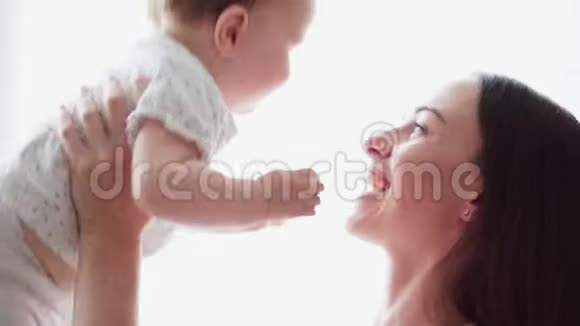 妈妈抱着可爱的宝宝在白色背景下和他玩耍视频的预览图