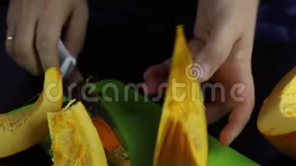 一个人用刀子在切割板上切一个橙色的南瓜世界素食日视频的预览图