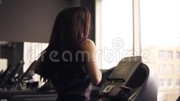 漂亮的黑发女孩留着长发穿着干燥的运动服在跑步机上跑步印第安录像视频的预览图