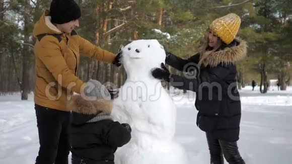 幸福的家庭妈妈爸爸和儿子正在冬天的城市公园堆雪人视频的预览图