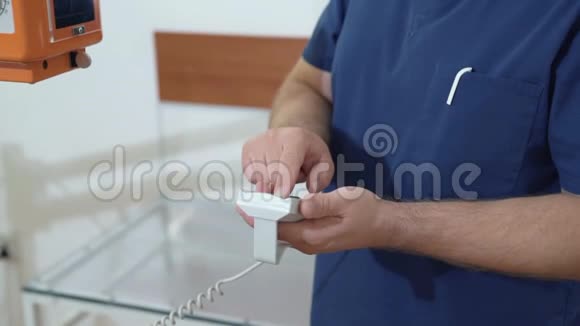 一位男医生使用遥控器调整X光机把的手拿在医用衣服上视频的预览图