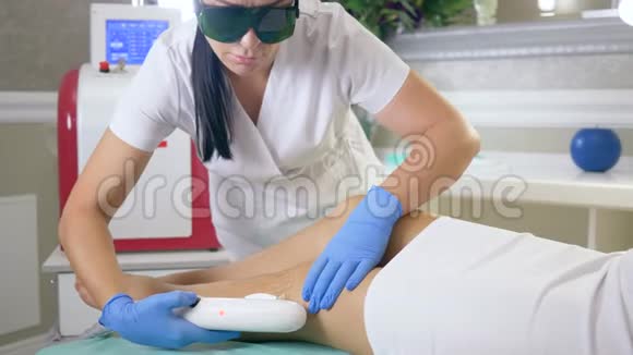 女性手术服务人员进入医疗眼镜确实脱毛客户妇女的腿使用激光仪器视频的预览图