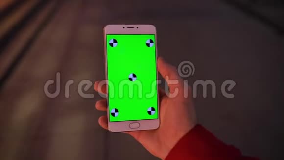 POV夜间行走的男性手中智能手机空白绿色屏幕视频的预览图