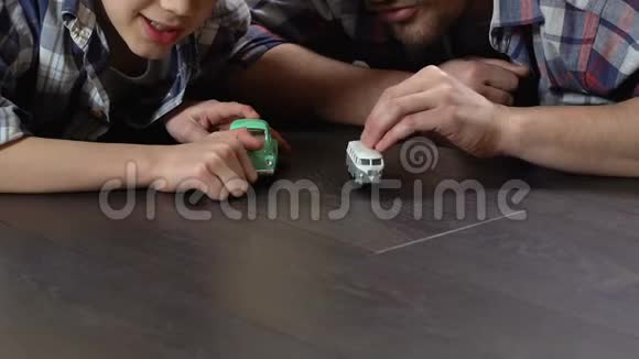 男孩和父亲在家里的地板上赛车比赛玩游戏视频的预览图