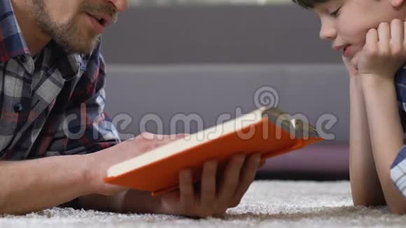 父亲读童话给儿子躺在地板上家庭休闲学前教育视频的预览图